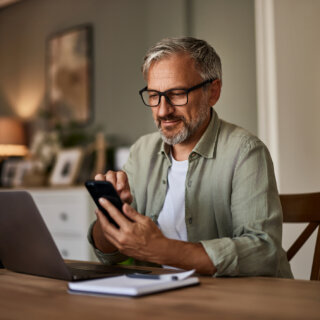 en företagare kollar på mobilen och datorn och undrar om han behöver ha tjänstepension.