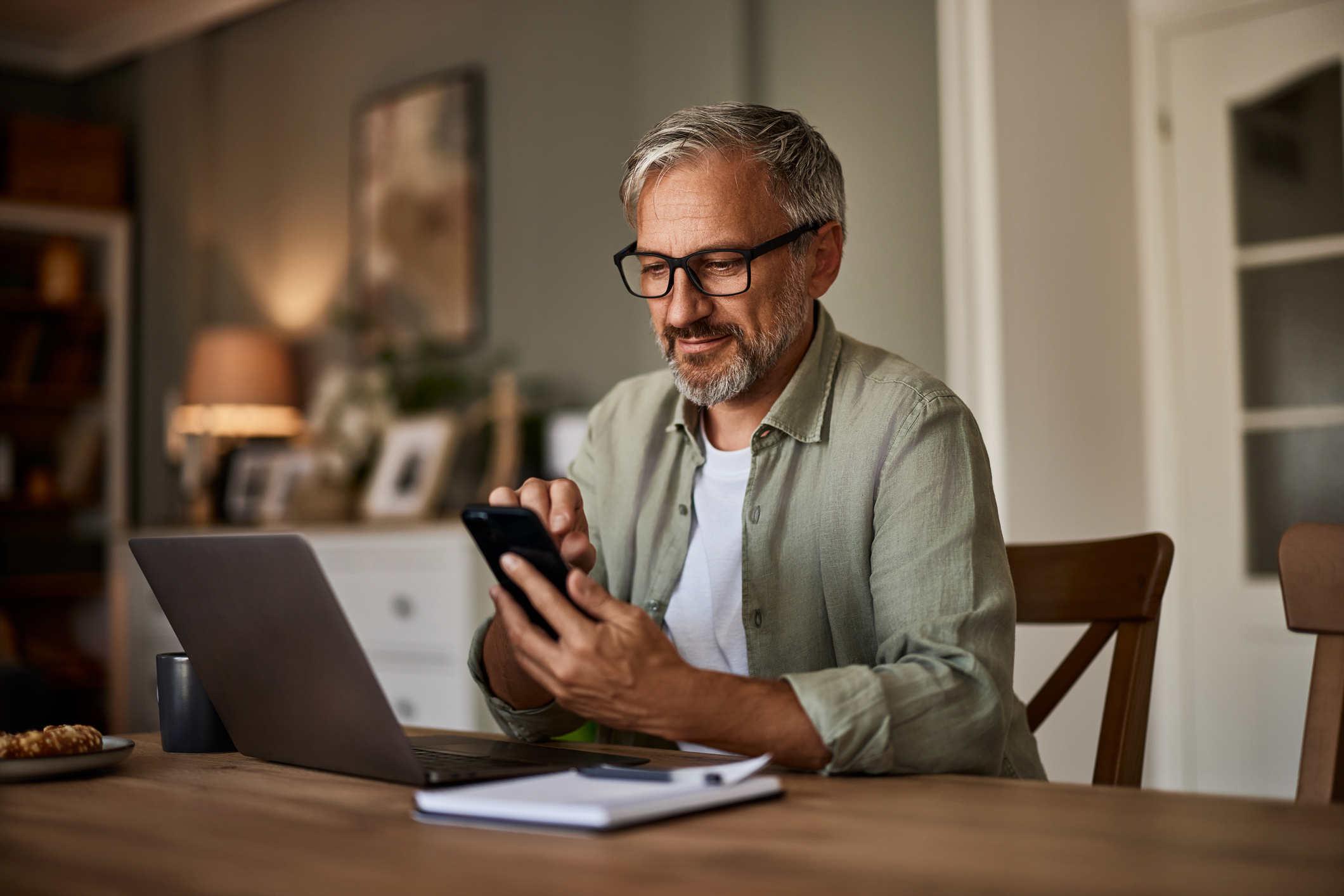 en företagare kollar på mobilen och datorn och undrar om han behöver ha tjänstepension.