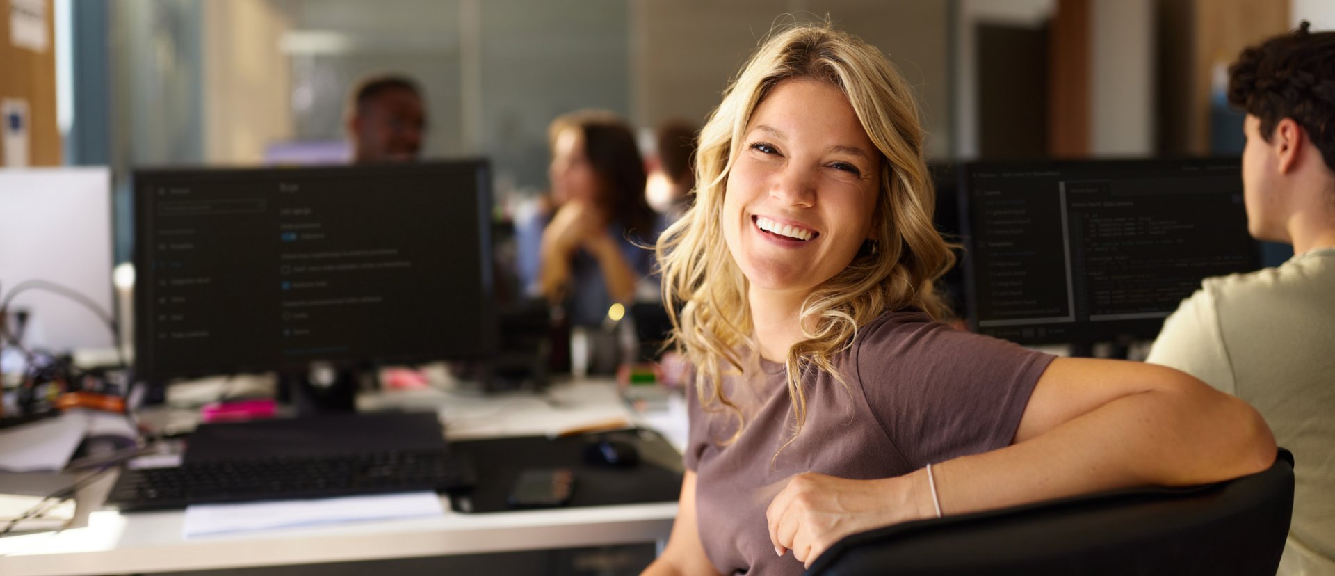 Kvinna sitter i ett kontorslandskap med sina kollegor.